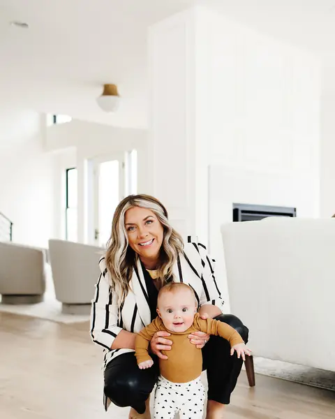 Ashlei crouching beside a toddler taking steps