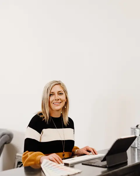 Ashlei working at a desk with a laptop and color swatches