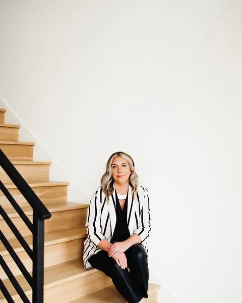 Ashlei sitting on a staircase in a striped blazer